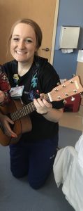 board certified music therapist playing a guitar in a hospital room